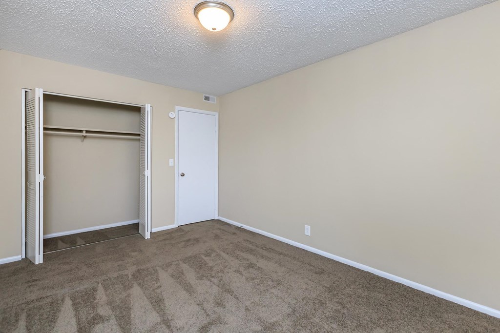an empty living room with a door to a closet