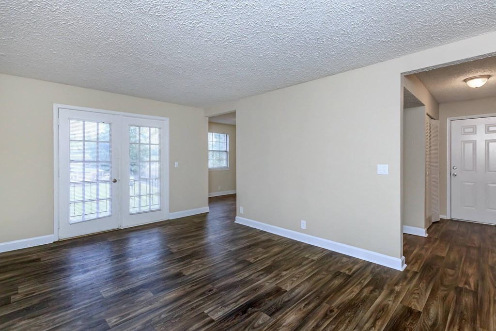 the living room and dining room of an empty house with wood flooring