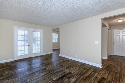 the living room and dining room of an empty house with wood flooring