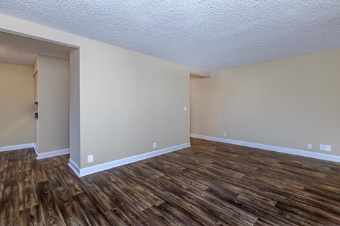 an empty living room with wood flooring and white walls