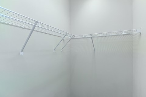 the walk in closet in a small room with white walls