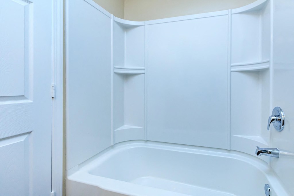 a white bathroom with a tub and white cabinets