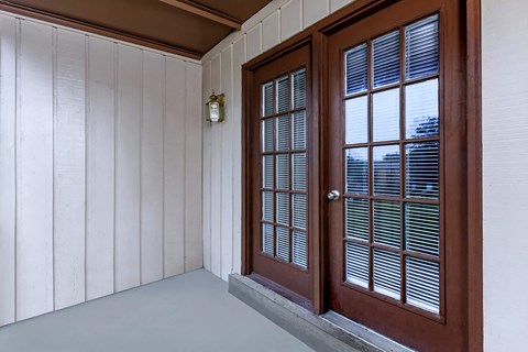 the front porch of a house with a wooden door and window