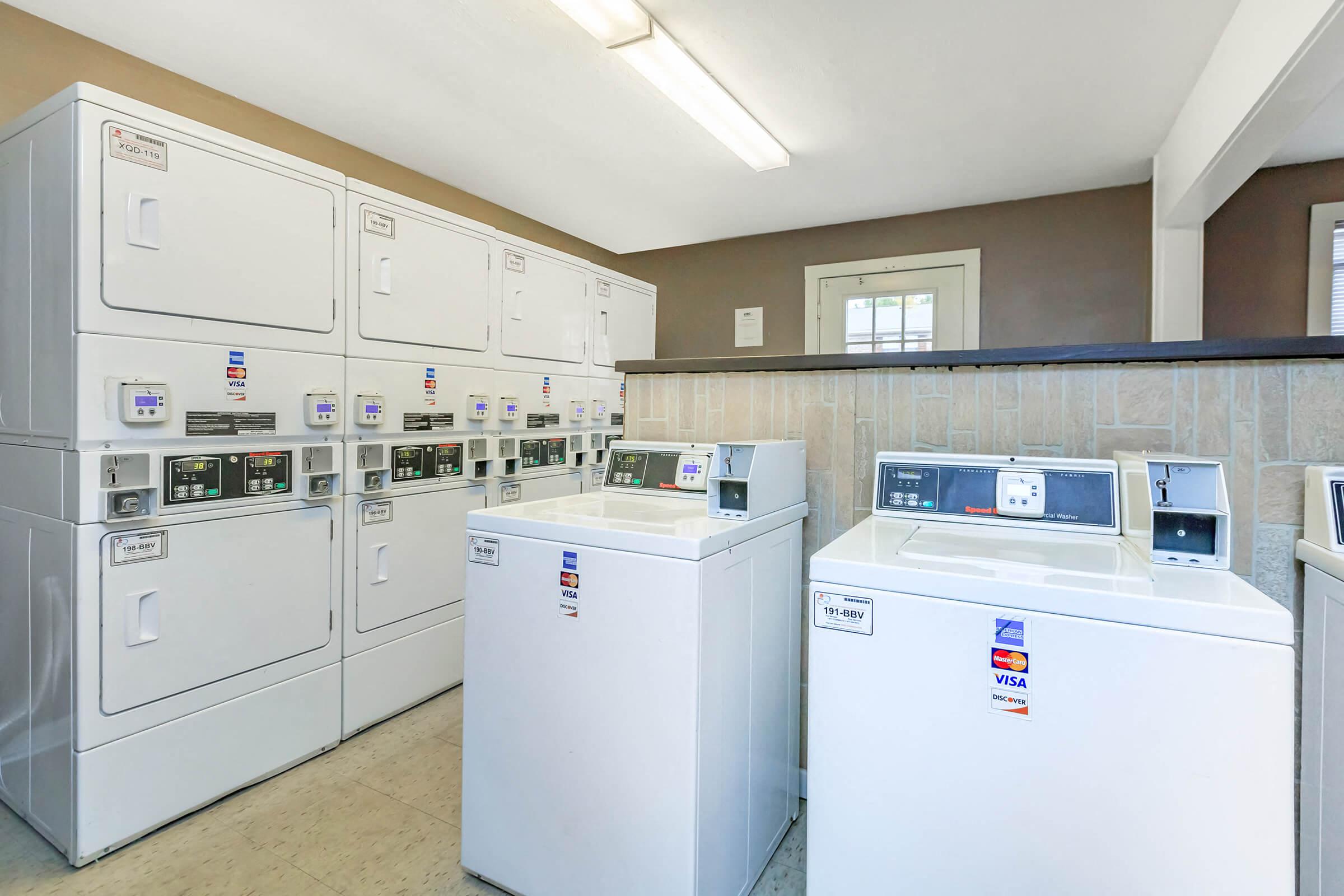 a group of washers and dryers in a utility room