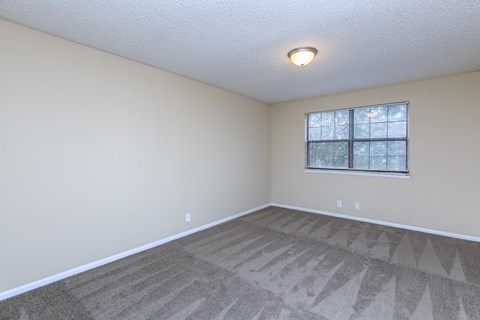 an empty living room with a window and carpet