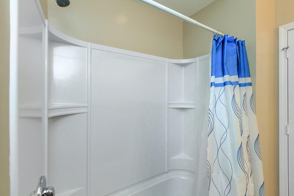 a white bathroom with a shower and a blue shower curtain