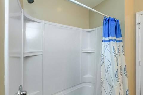 a white bathroom with a shower and a blue shower curtain