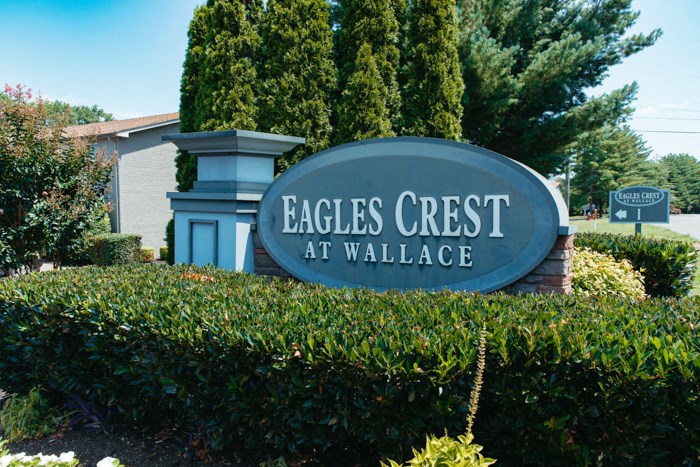 the sign for eagles crest at wallace is in front of a hedge