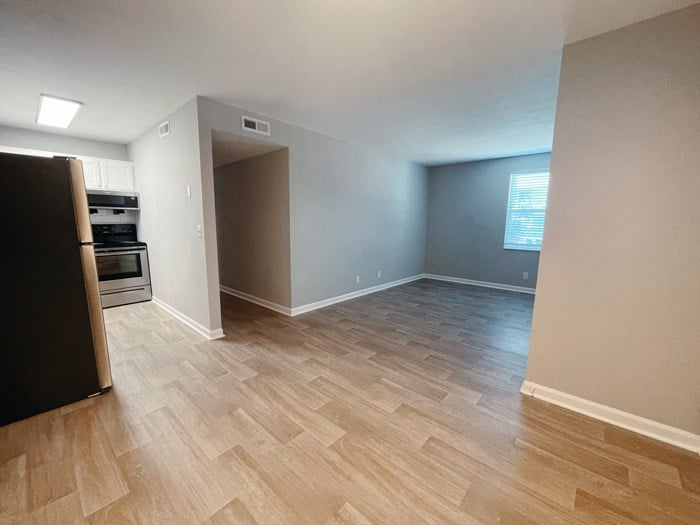 an empty living room and kitchen with wood flooring