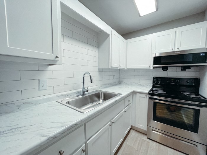 an empty kitchen with white cabinets and a sink