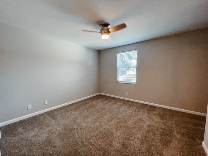 an empty room with carpet and a ceiling fan