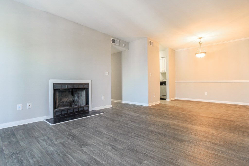 an empty living room with a fireplace and wood flooring