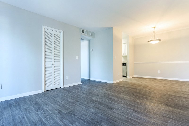 an empty living room with wood flooring and a door to a bathroom
