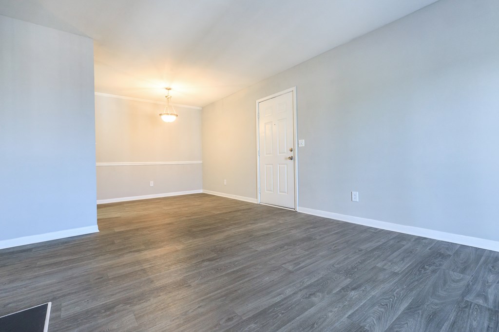 an empty living room with wood flooring and a white door