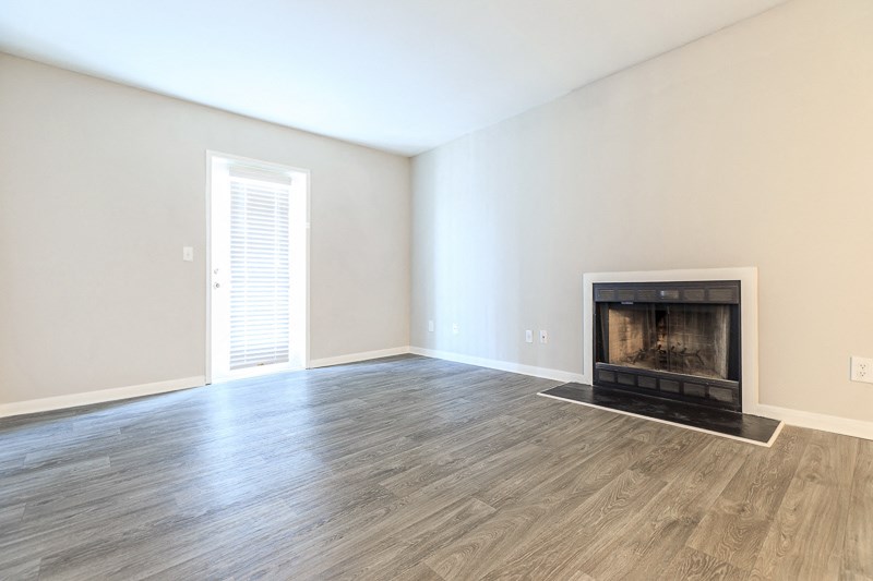 an empty living room with a fireplace and wooden floors