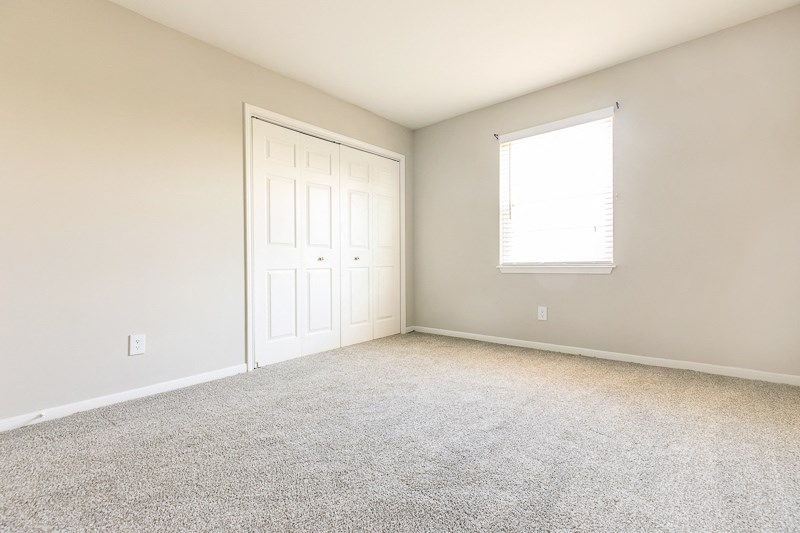 an empty room with a window and a white door
