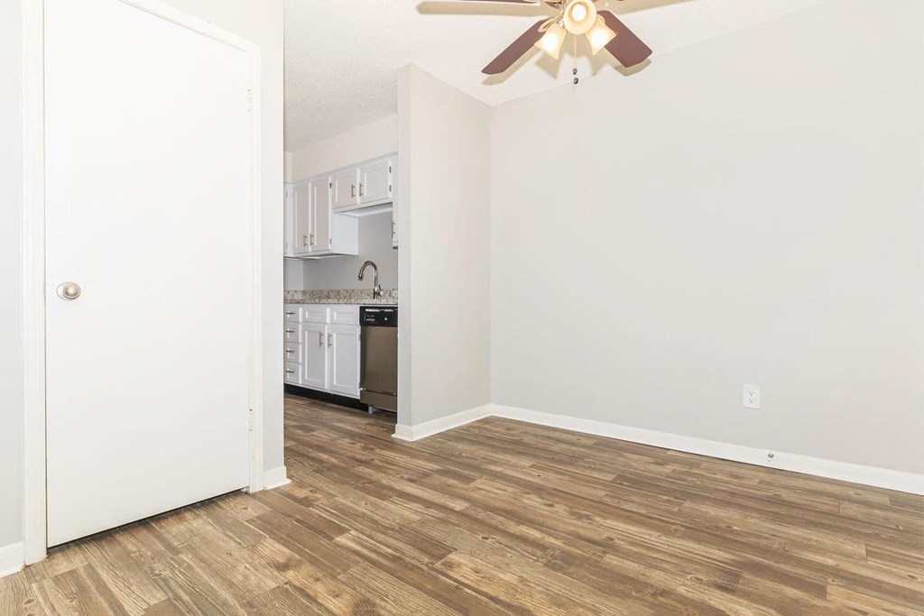 an empty living room with a ceiling fan and a kitchen
