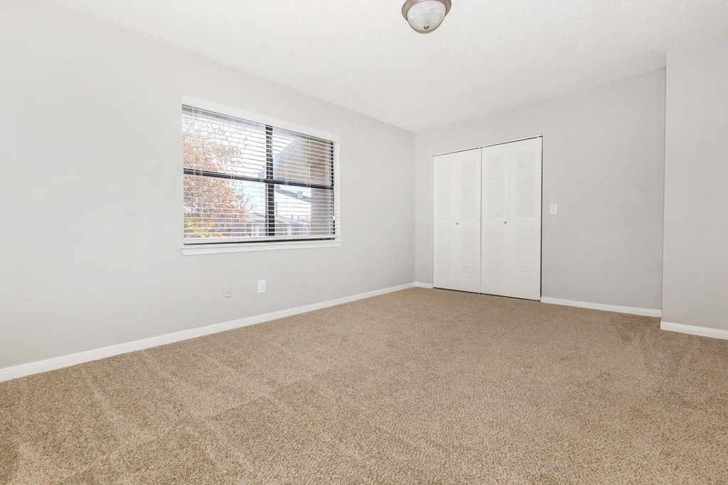 an empty living room with a window and a closet