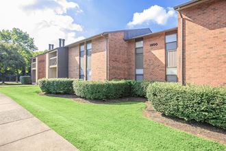 a brick building with green grass and a sidewalk