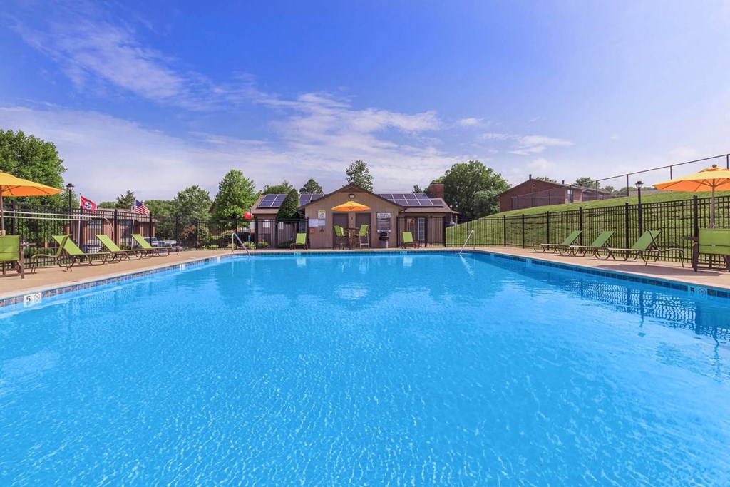 a large pool with chairs and umbrellas near a house