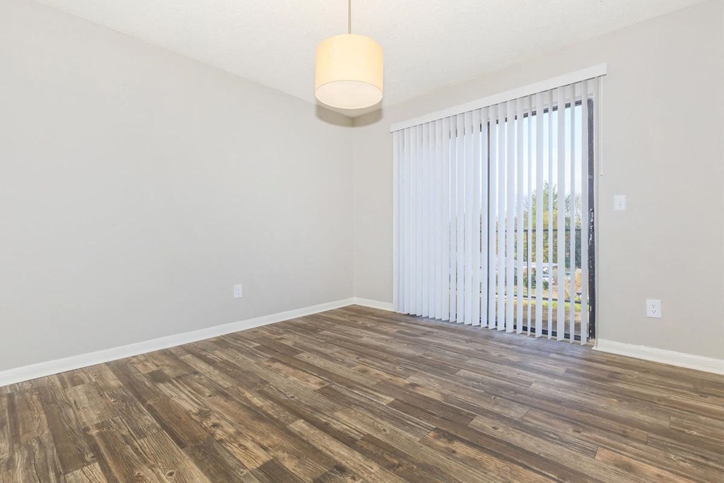 an empty living room with a large window and wood flooring