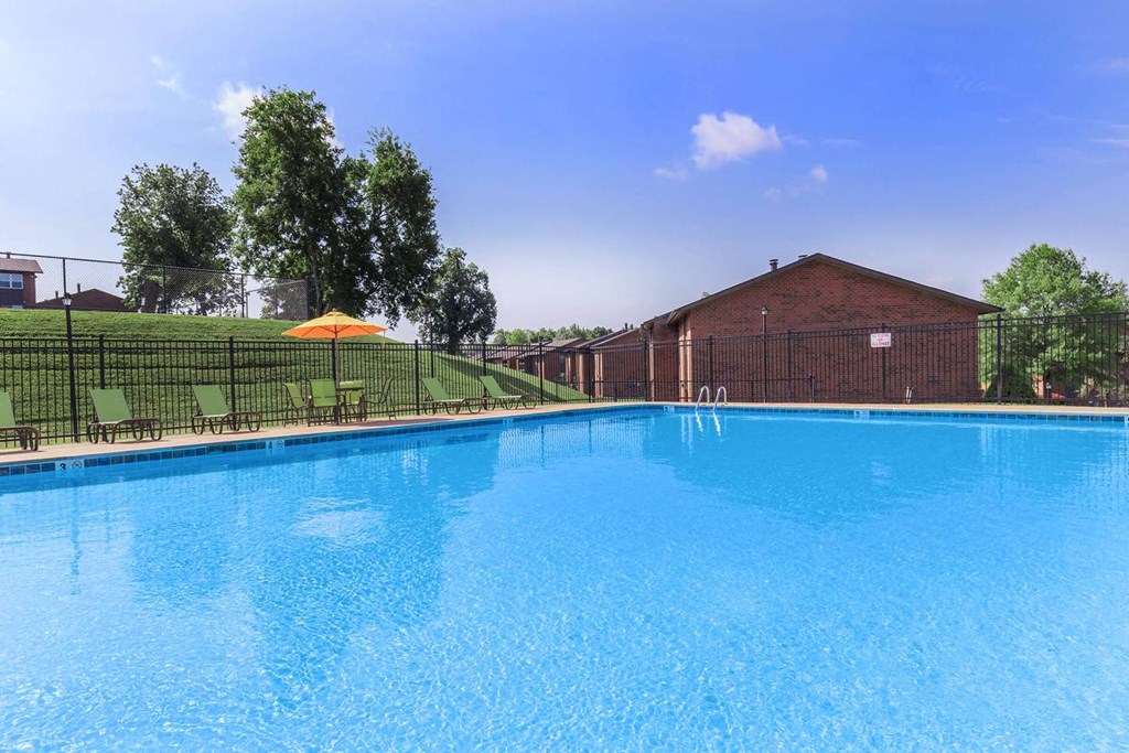 a large pool with a fence around it next to a brick building