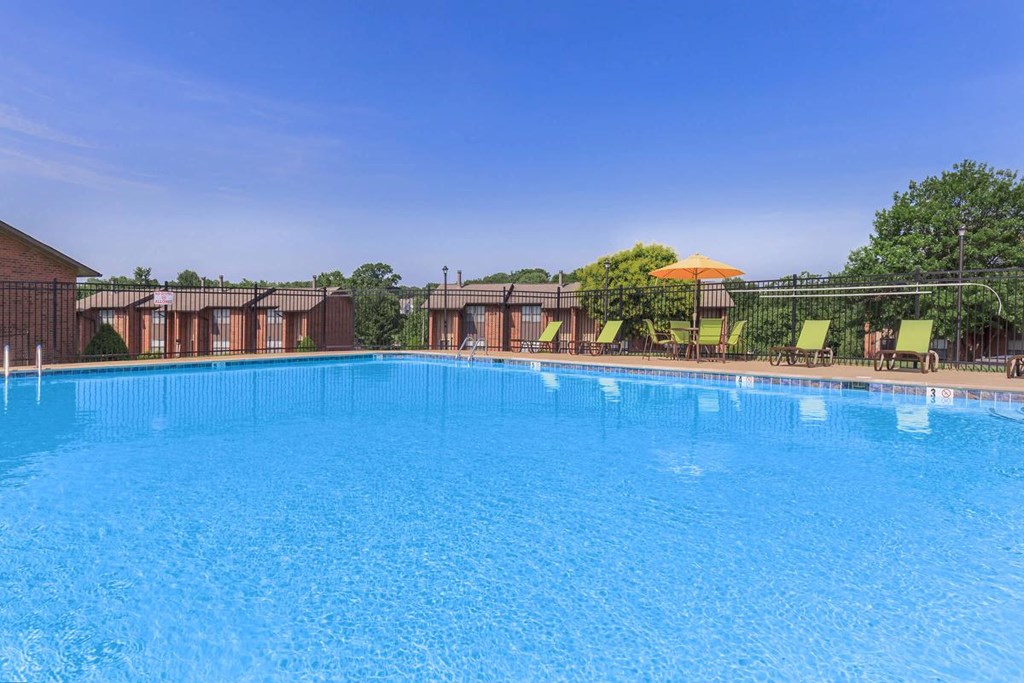 a large pool with chairs and an umbrella at a resort