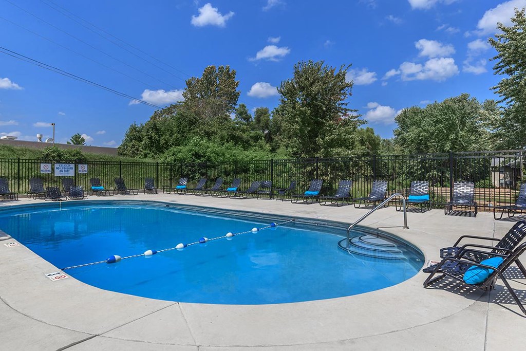 a swimming pool with chairs and a fence around it