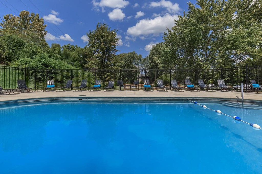 a swimming pool with blue water and chairs around it