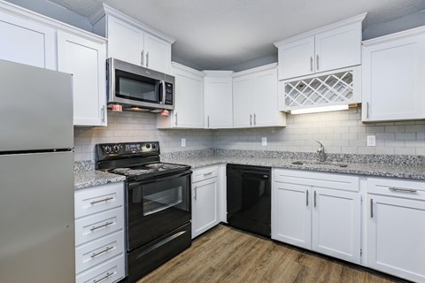 A kitchen with white cabinets and black appliances.