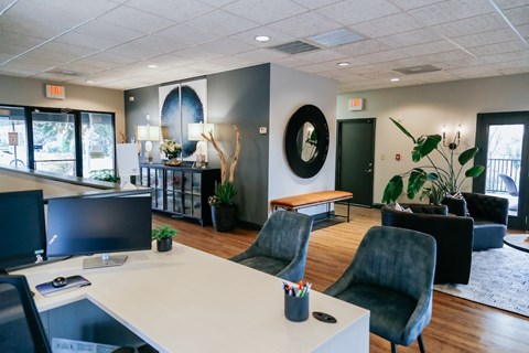 A modern office space with a white desk and black chairs.