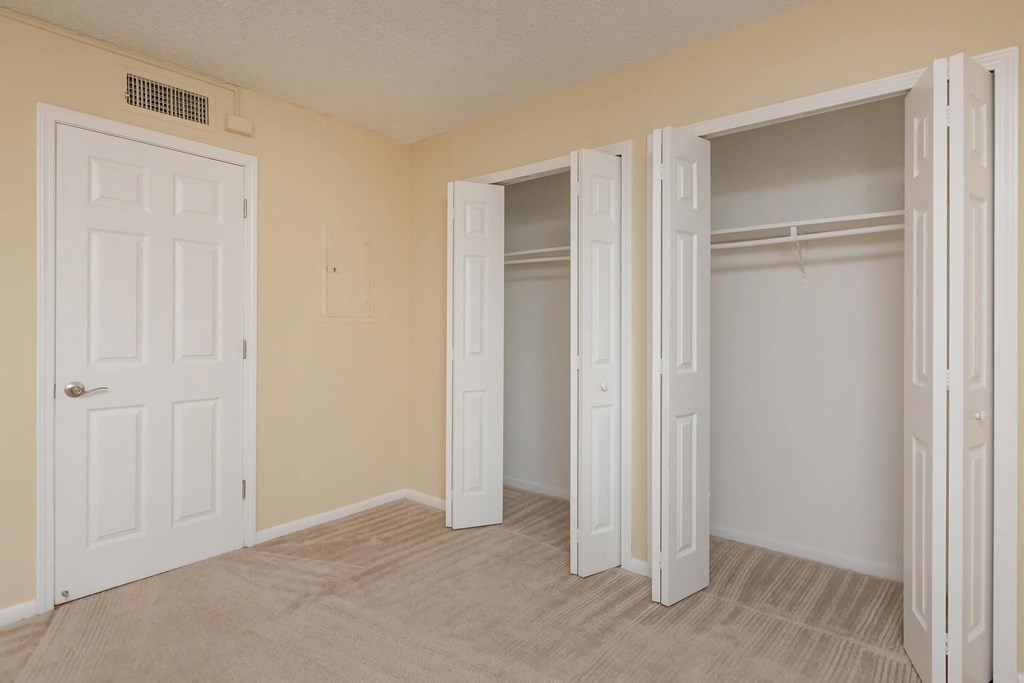 an empty bedroom with two closets and two doors