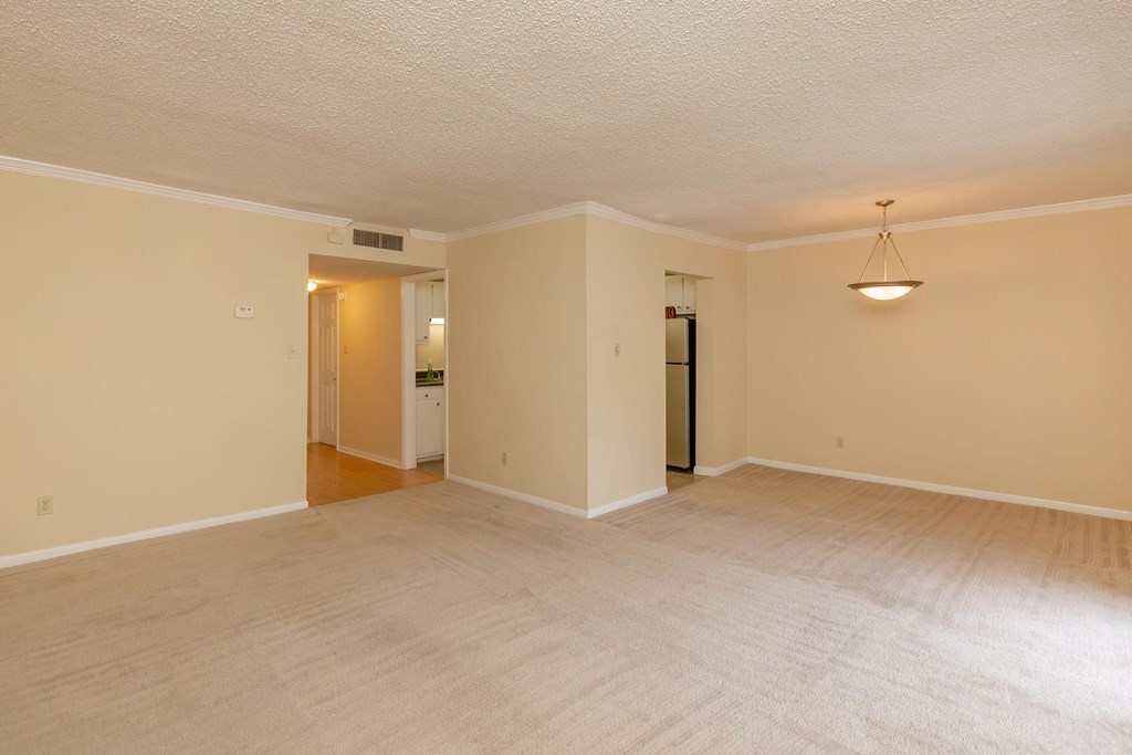the living room and dining room of an empty house with a white carpet and a