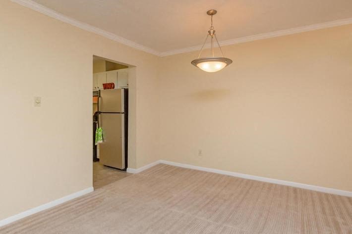 an empty living room with a refrigerator in it