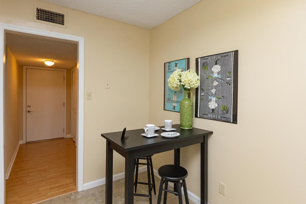 a dining room table with two stools and a vase with flowers