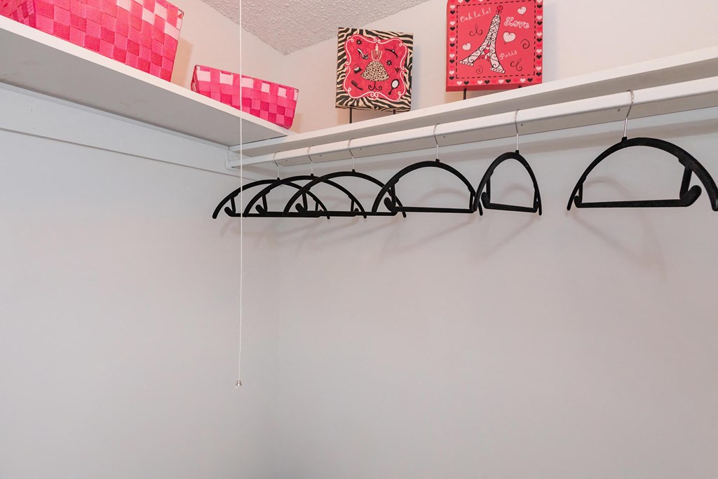 a closet with white walls and hooks and red and pink decorations