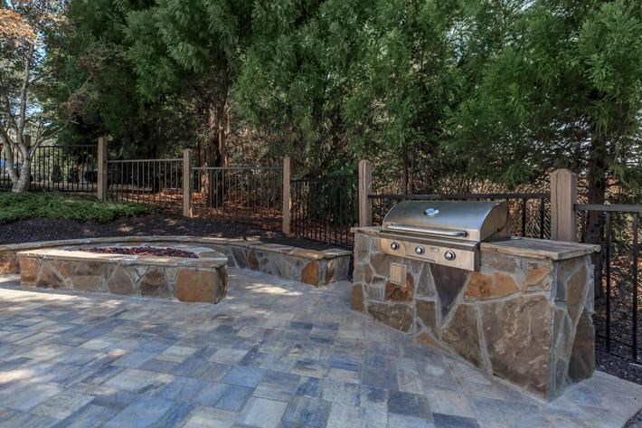 a stone patio with a grill and a fire pit