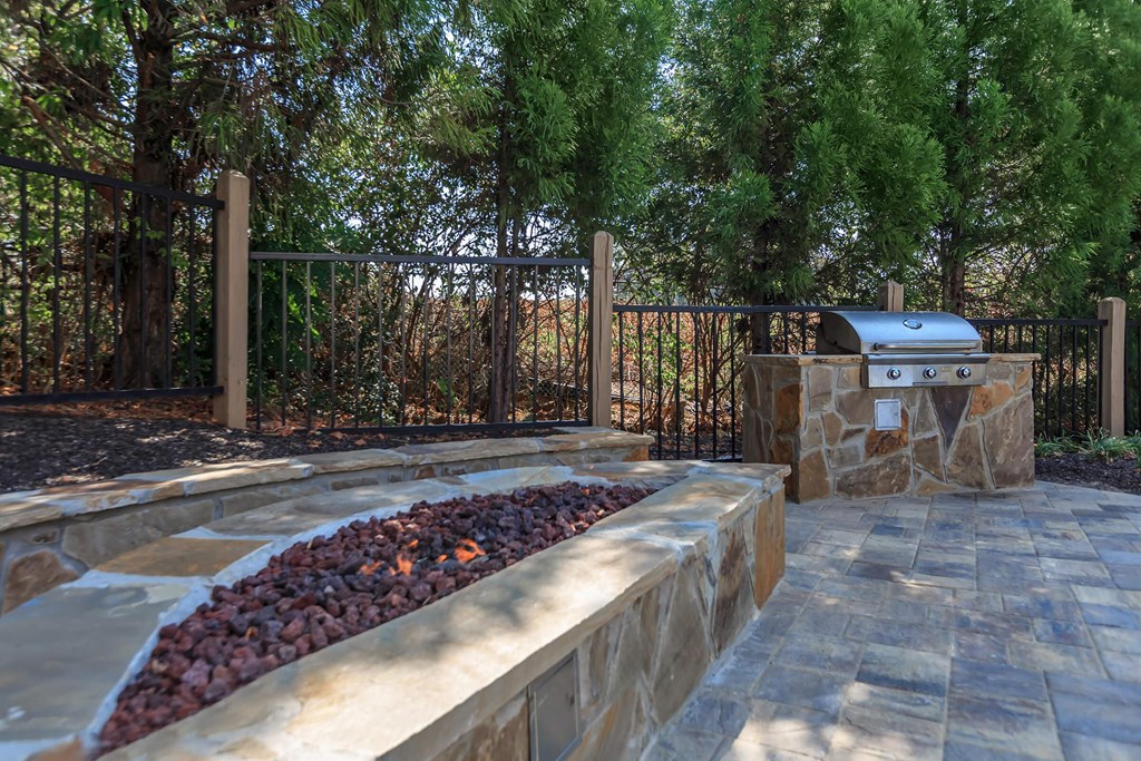 a stamped concrete patio with a fire pit and a grill