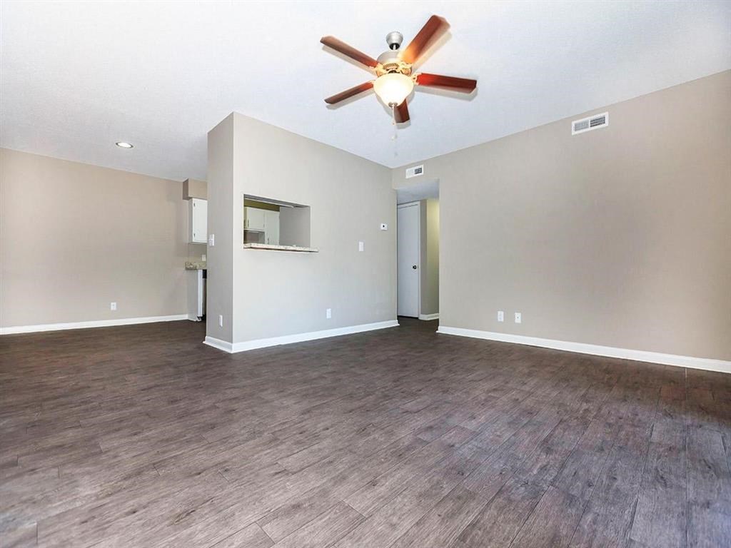 an empty living room with a ceiling fan