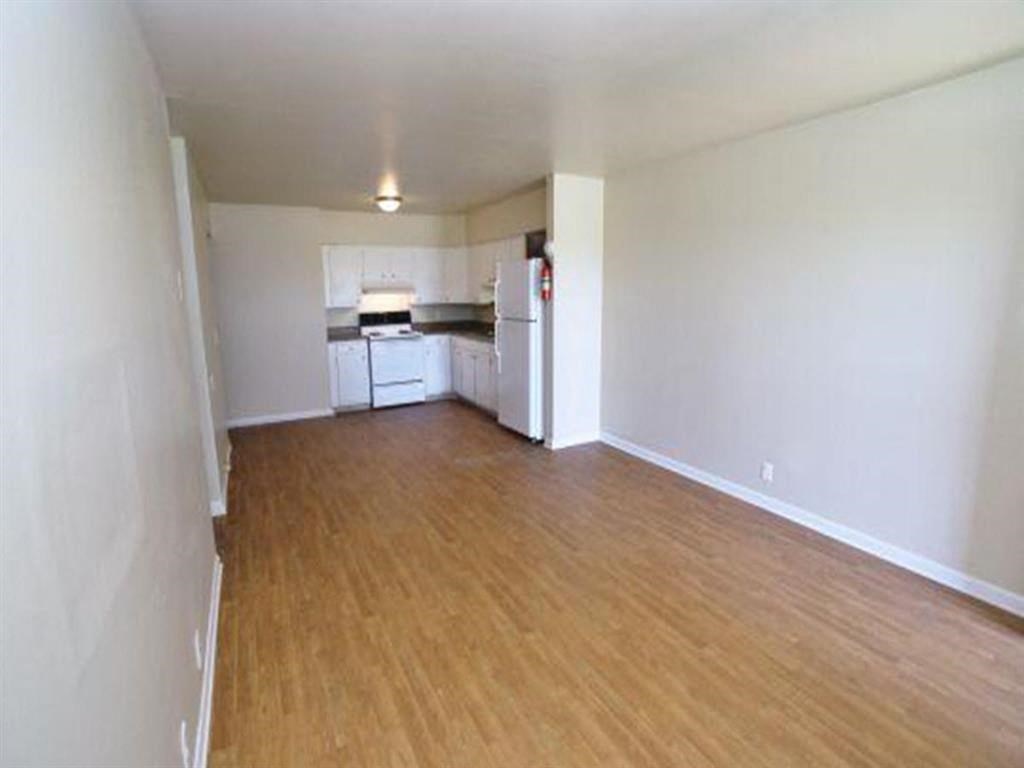 an empty living room and kitchen with a wood floor
