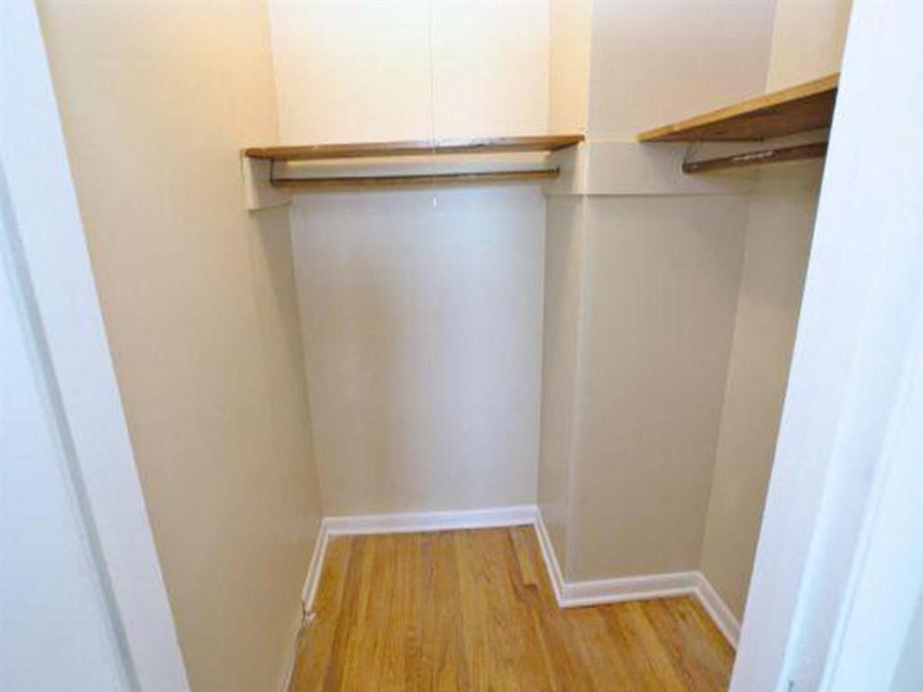 a small closet with white walls and a wood floor