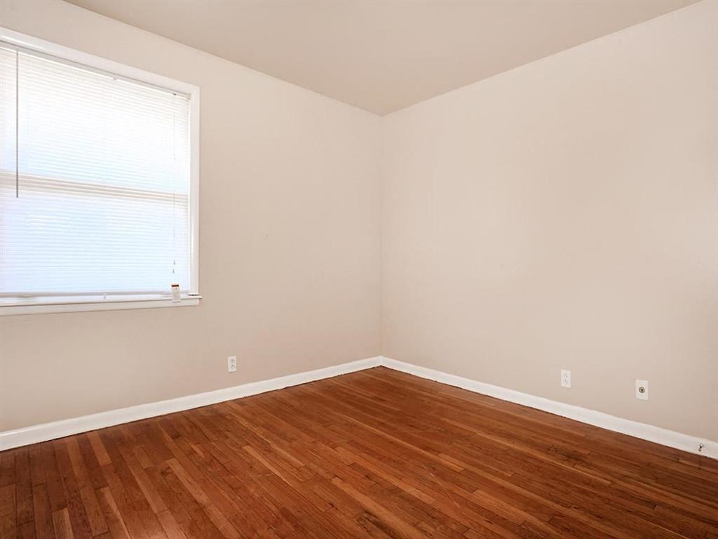 an empty room with wooden floors and a window