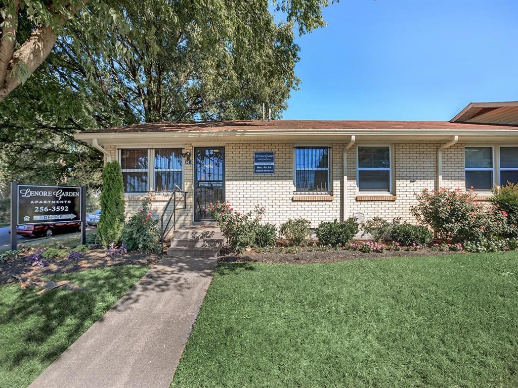 a brick house with a lawn and a sign in front of it