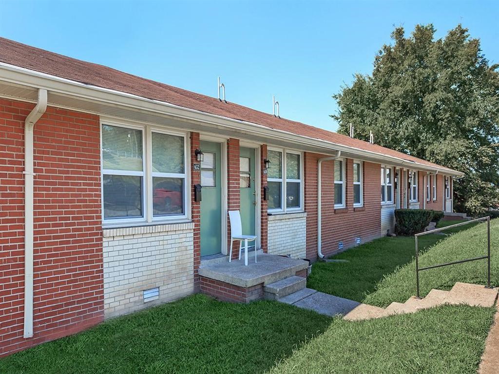 a small brick house with a lawn and a white chair