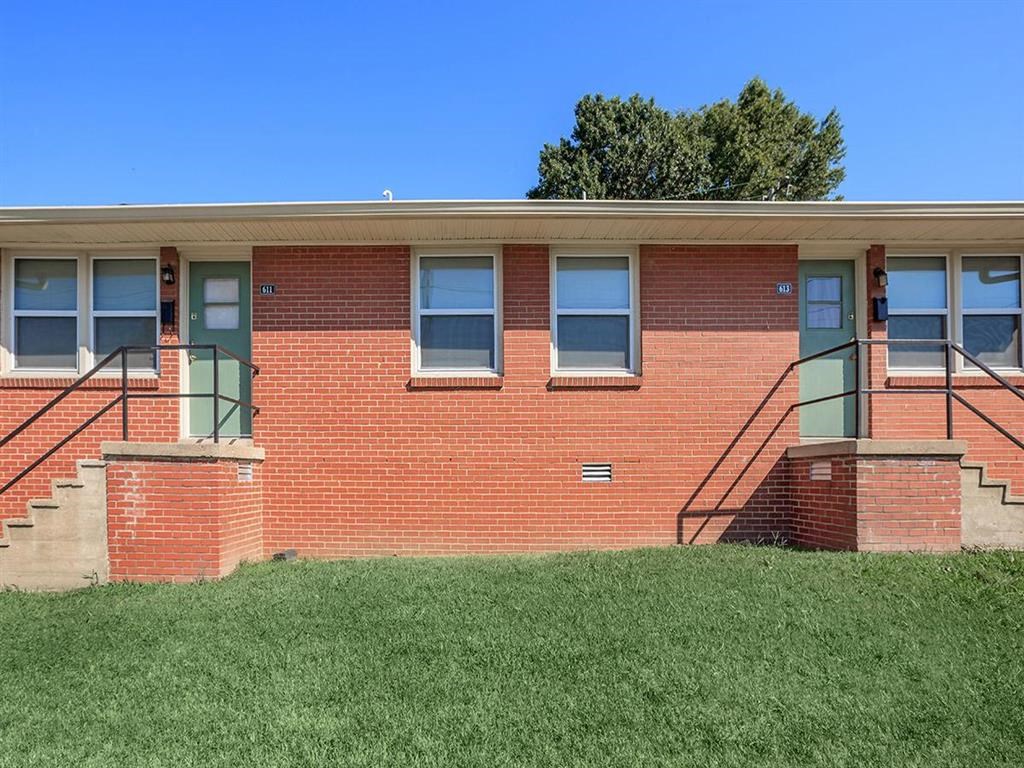 the front of a brick building with green doors and windows