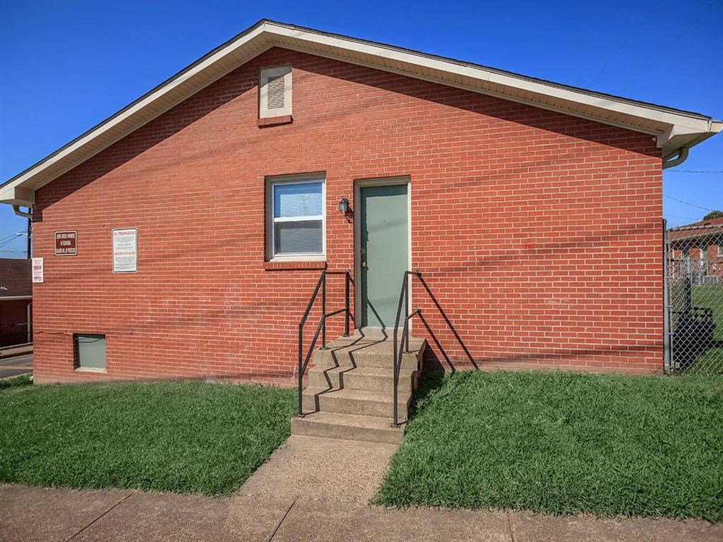 a red brick building with stairs and a green door