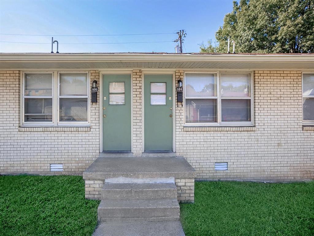 the front of a brick house with green doors