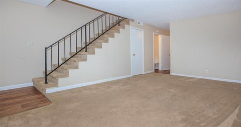 a living room with a staircase and a carpeted floor