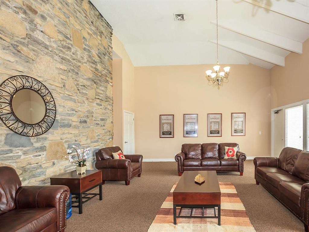a living room with leather furniture and a stone wall