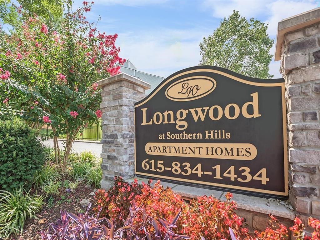 a sign for longwood apartments in front of a stone wall